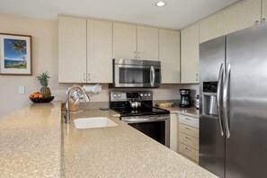 A modern kitchen with stainless steel appliances, a granite countertop, and light-colored cabinetry. - Napili Point 3 Waterfront Villas, Sleeps 16 | Car Incl. w/ 6 nights | ML-4083 by KBM (Lahaina)
