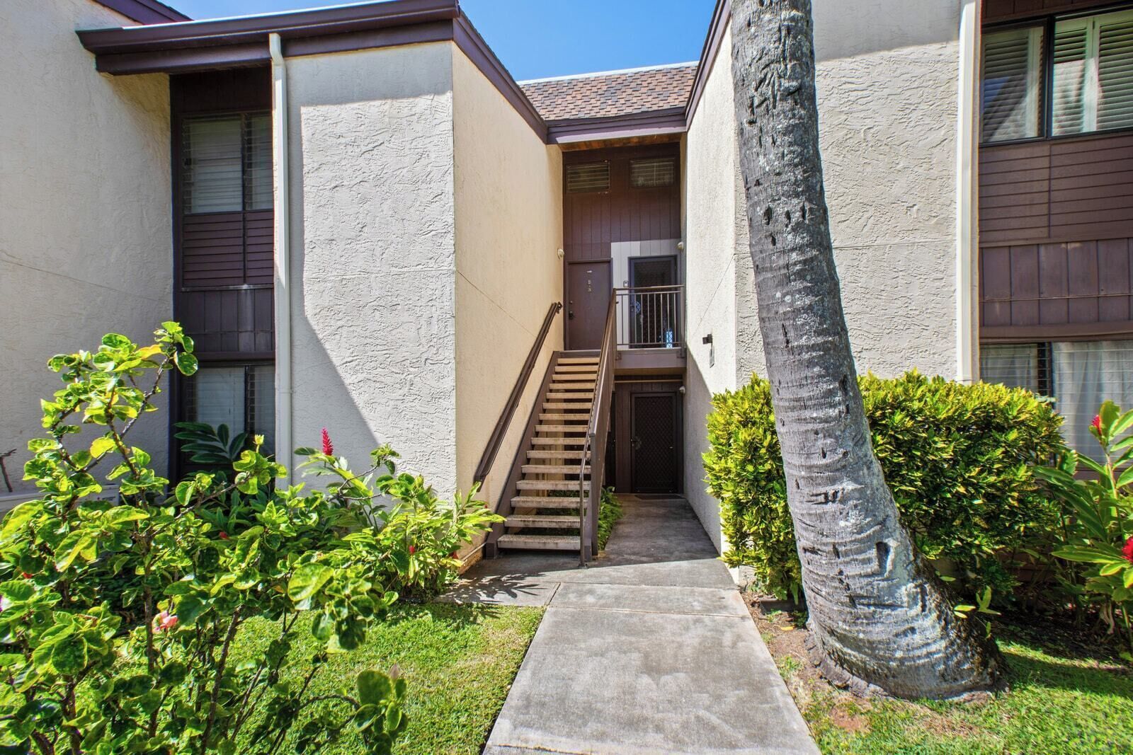 A residential building with a concrete pathway leading to a wooden staircase.