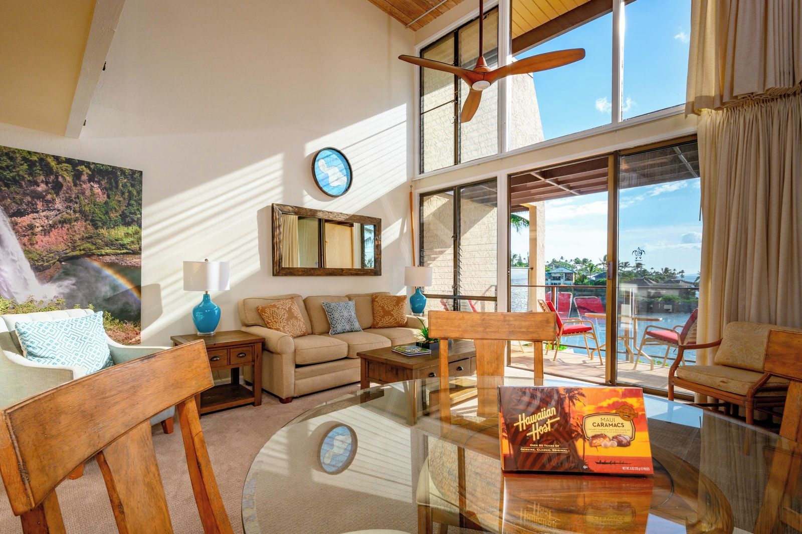 A spacious living area with a glass table, a sofa, and a view of the outdoors.