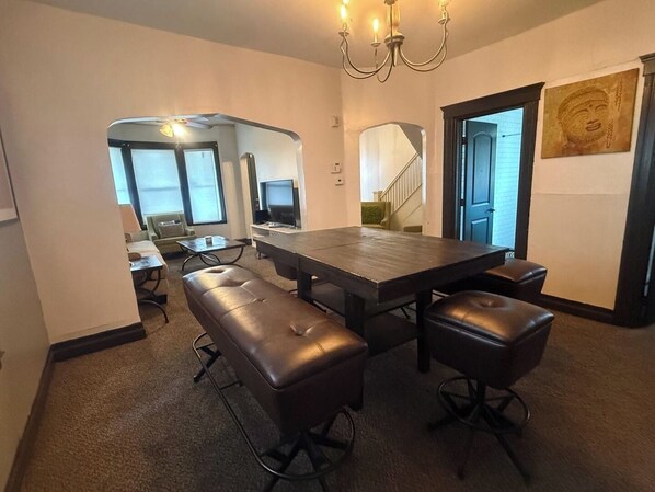 A modern dining area with a large rectangular table, four leather benches, and a chandelier.