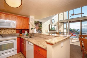 A kitchen with granite countertops, wooden cabinets, a microwave, stove, and a sink. - Napili Point 3 Water Front Villas, Sleeps 18 | Car Incl. w/ 6 nights | ML-4086 by KBM (Lahaina)