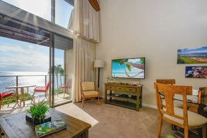 A balcony with a view of the sea, a TV on the wall, and a wooden dining table with chairs. - Napili Point 3 Water Front Villas, Sleeps 18 | Car Incl. w/ 6 nights | ML-4086 by KBM (Lahaina)