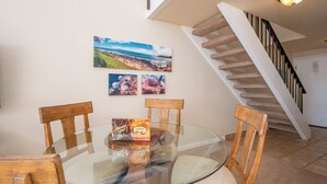 A dining area with a glass table, wooden chairs, and a Hawaiian-themed box. - Napili Point 3 Water Front Villas, Sleeps 18 | Car Incl. w/ 6 nights | ML-4086 by KBM (Lahaina)