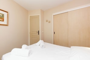 Ein Hotelzimmer mit einem Bett, zwei Türen und einem gerahmten Bild an der Wand.