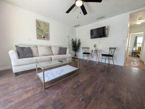 A living room with a sofa, coffee table, and a TV mounted on the wall. - The Beach Shack - 1BR Neptune Getaway (Neptune Beach)