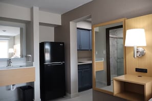 A modern kitchen with a black refrigerator, a wooden cabinet, and a glass shower enclosure. - Studio 6 Suites (Warsaw)