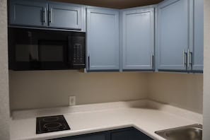 Une cuisine avec des meubles de couleur bleu clair, un micro-ondes noir et un évier en acier inoxydable.
