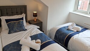 Een hotelkamer met twee bedden, een nachtkastje met een lamp en een raam met uitzicht.