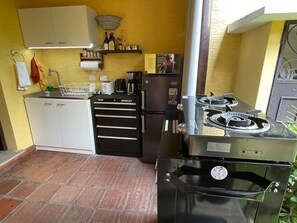 Eine kleine Küche mit Gasherd, Kühlschrank, Kaffeemaschine und einer Arbeitsfläche.
