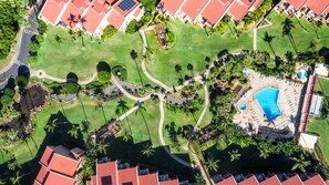 An aerial view of a resort with a swimming pool, palm trees, and a well-maintained lawn. - Kihei Ground Floor Unit: AC, Steps to Pool & Beach (Kihei)