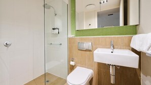 A modern bathroom with a glass shower enclosure, a white toilet, a sink, and a mirror above the sink. - Studio 1-bedroom apartment with AC in charming Gungahlin (Gungahlin)
