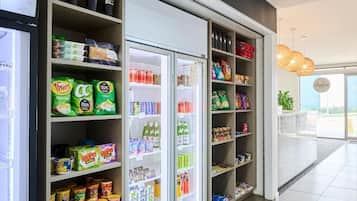 A grocery store interior with shelves stocked with snacks, beverages, and canned goods.