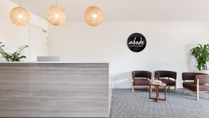 A reception area with a modern desk, three hanging spherical light fixtures, and a sign that reads 'abode apartment hotels.' - Studio 1-bedroom apartment with AC in charming Gungahlin (Gungahlin)