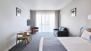 A hotel room with a bed, a TV, a sofa, a chair, and a small table. - Studio 1-bedroom apartment with AC in charming Gungahlin (Gungahlin)