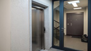 Un couloir avec une porte-fenêtre coulissante, une porte portant un numéro et un escalier.