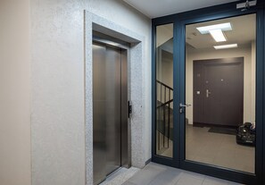 Un passadís amb una porta corredissa de vidre, una porta amb un número i una escala.
