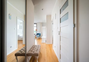 Un passadís amb una panxa, una porta i una visió d'un dormitori amb un llit i una cadira.