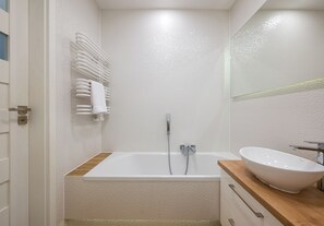 Ett badrum med badkar, handfat och handduksställ.