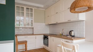 Une cuisine avec des meubles blancs, un plan de travail en bois et un luminaire suspendu.