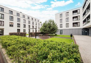 Ett modernt lägenhetskomplex med en innergård, inklusive en gräsyta och ett träd.