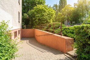 A curved brick pathway leading to a building entrance with a metal railing and greenery. - Grzegórzki Cozy Apartment (Kraków)