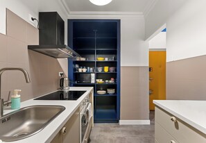 Eine kleine Küche mit Spüle, Herd und einem blauen Schrank mit Regalen.