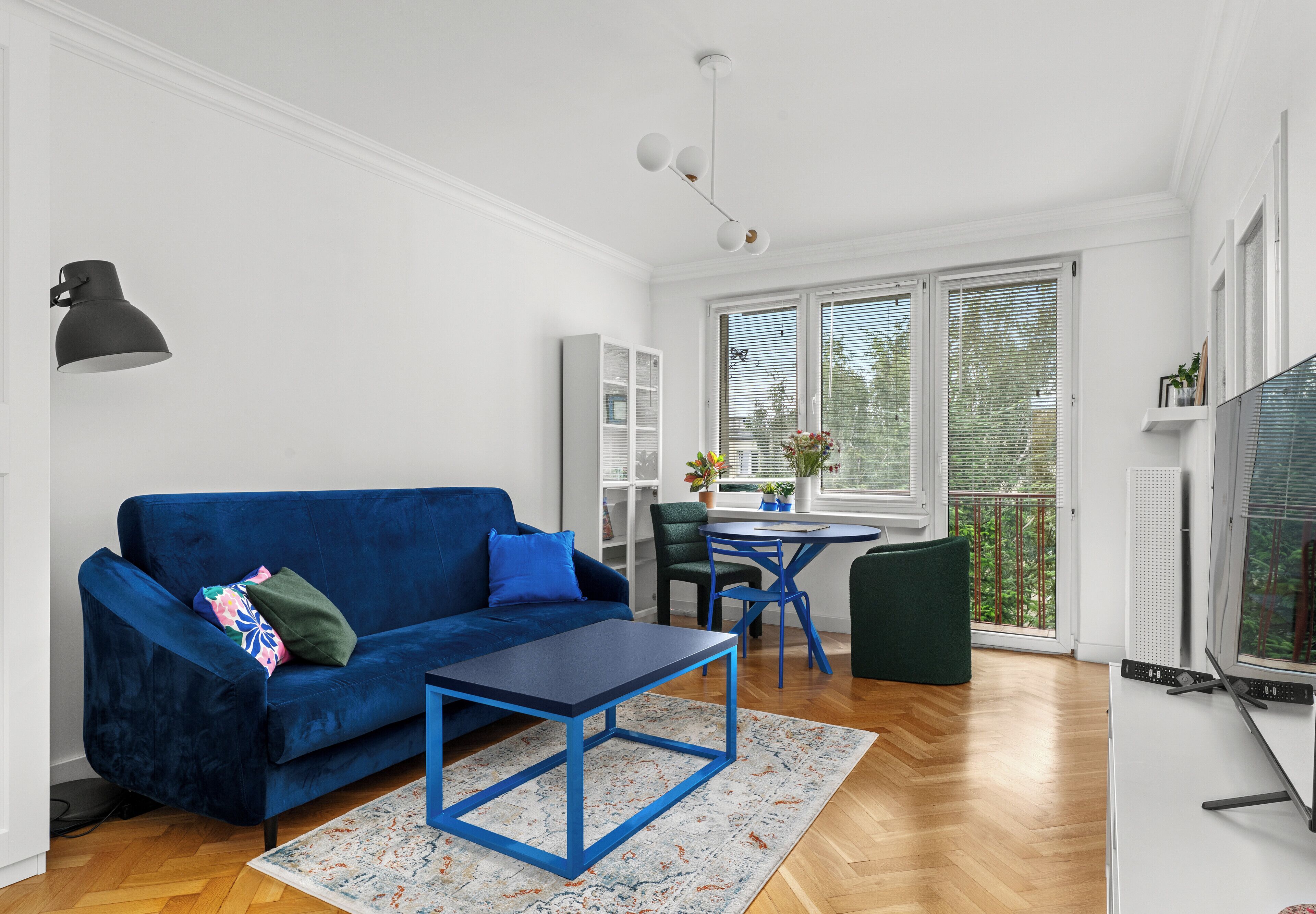 A living room with a blue sofa, a small table, and a TV.
