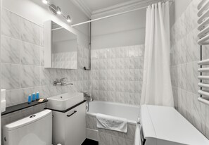 Ein modernes Badezimmer mit Toilette, Waschbecken, Badewanne und Spiegel.