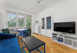 Ein modernes Wohnzimmer mit Sofa, Tisch, Stühlen, Fernseher und Kamin.