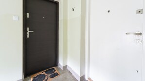 A hallway with a dark door, a white door with the number 104, and a door with the number IV. - Grzegórzki Cozy Apartment (Kraków)