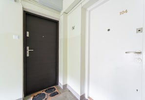 A hallway with a dark door, a white door with the number 104, and a door with the number IV. - Grzegórzki Cozy Apartment (Kraków)