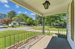 A covered porch with a metal railing, a street view, and a lamp post.