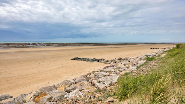 Une plage bordée d’une côte rocheuse et offrant une vue dégagée sur la mer.