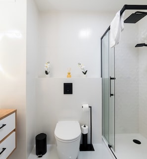 Une salle de bain moderne équipée de toilettes, d’un bidet et d’une douche à parois de verre.