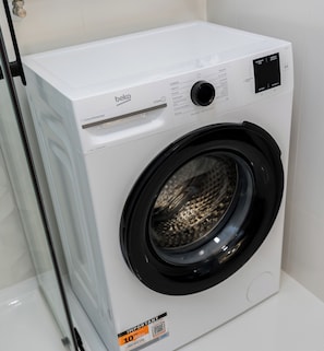 Une machine à laver blanche, fixée au mur, dotée d’un panneau de commande, d’une porte noire et d’une étiquette indiquant « 10 : important ».