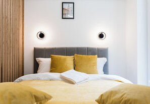 A neatly made bed with a grey headboard, two mustard-colored pillows, and a white blanket. - Garbary Old Town Apartment #11 (Poznań)