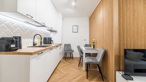 Een moderne keuken met witte kastjes, een houten aanrechtblad en een eethoek met een tafel en stoelen.