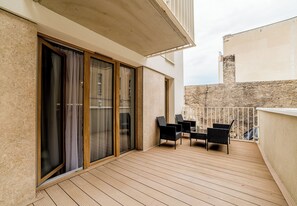 A balcony with wooden flooring, sliding glass doors, and two black wicker chairs. - Garbary Old Town Apartment #11 (Poznań)