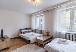 A bedroom with two beds, a wooden desk, a chair, and a window with curtains. - Jagiellońska Comfort Apartment (Rzeszów)