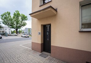 Ein Gebäude mit einer schwarzen Tür, einem kleinen Fenster und einem gepflasterten Bürgersteig.