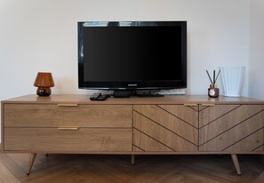 Ein Holz-TV-Schrank mit einem Flachbildfernseher, einer Fernbedienung und einem Dekoelement.
