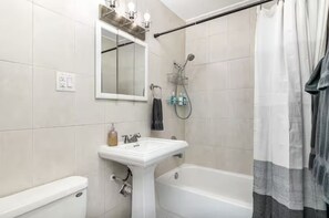 Un baño con lavabo blanco, espejo y ducha.