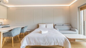 A modern bedroom with a bed, bedside tables, a desk, and a sofa. - Warta River Chic Studio (Poznań)