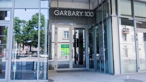 A building entrance with a sign reading 'GARDBARY 100' and a glass door. - Warta River Chic Studio (Poznań)