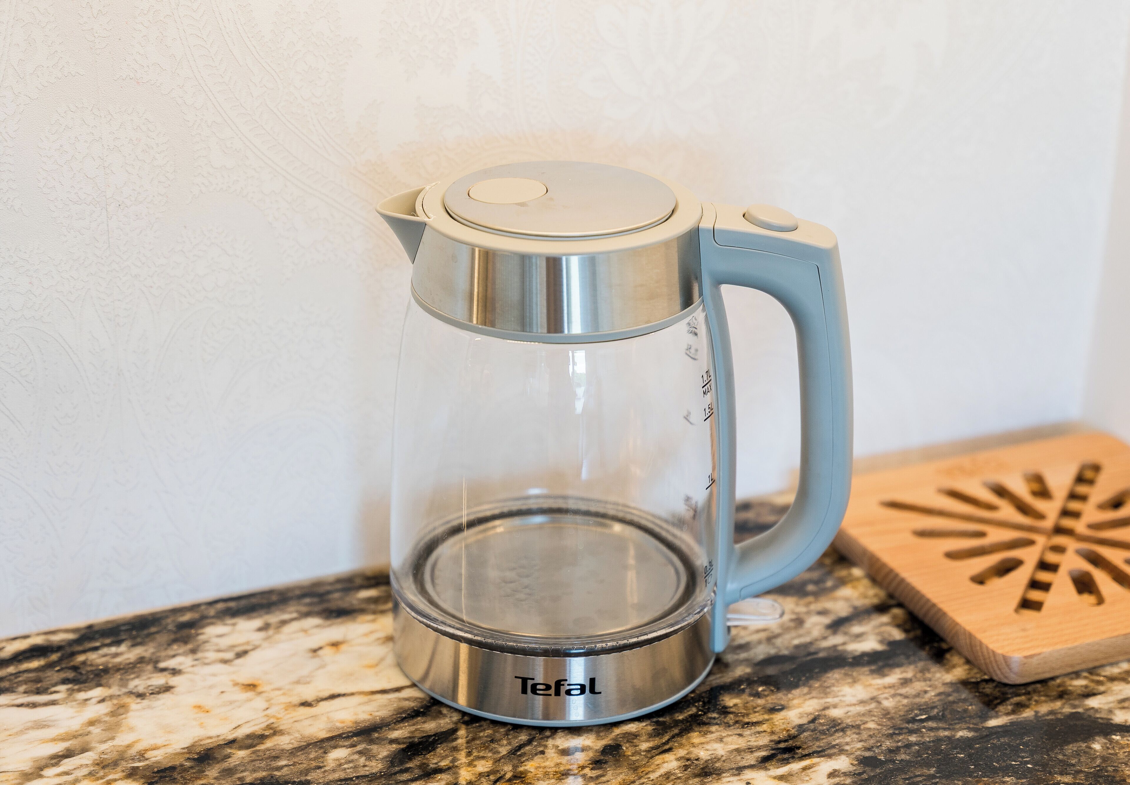 A clear glass coffee pot with a metallic base labeled 'Tefal' on a granite countertop.