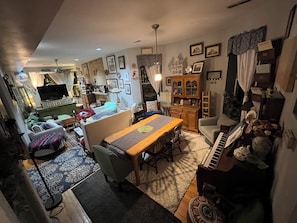 Un salon chaleureux avec une table à manger, des canapés, un piano et un téléviseur.