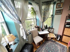 A cozy room with a window, a chair, a small table, and a bookshelf.