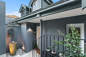 A residential building with a grey exterior, a visible window, a balcony with a railing, and a potted plant. - SPRU7 - Neutral Bay Sanctuary | Sunlit Home (Neutral Bay)