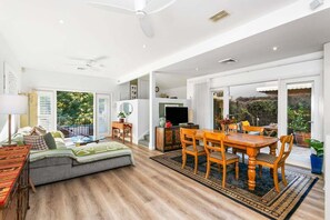 A spacious living room with a sofa, a dining table with chairs, a ceiling fan, and a large window. - SPRU7 - Neutral Bay Sanctuary | Sunlit Home (Neutral Bay)