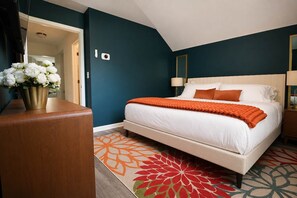 Une chambre d’hôtel avec un lit, une table de chevet, une lampe, un vase et une porte.